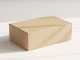A cardboard product packaging box rests on a white table. The box has text that says "BOX MOCKUP" and "PACKAGE MOCKUP."