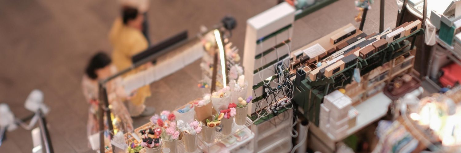 Overhead view of three displays side-by-side at an indoor pop-up shop, each displaying various trinkets to sell.