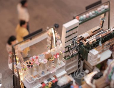 Overhead view of three displays side-by-side at an indoor pop-up shop, each displaying various trinkets to sell.