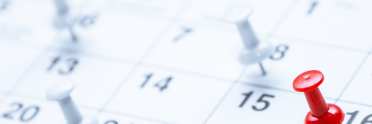 A red pushpin marks the 16th on a calendar while blurred white pins in the background highlight other scheduled dates.