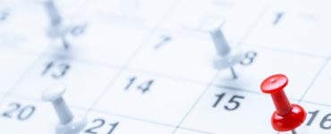 A red pushpin marks the 16th on a calendar while blurred white pins in the background highlight other scheduled dates.