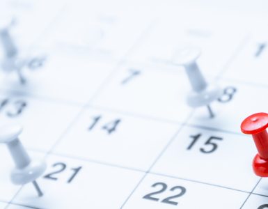 A red pushpin marks the 16th on a calendar while blurred white pins in the background highlight other scheduled dates.